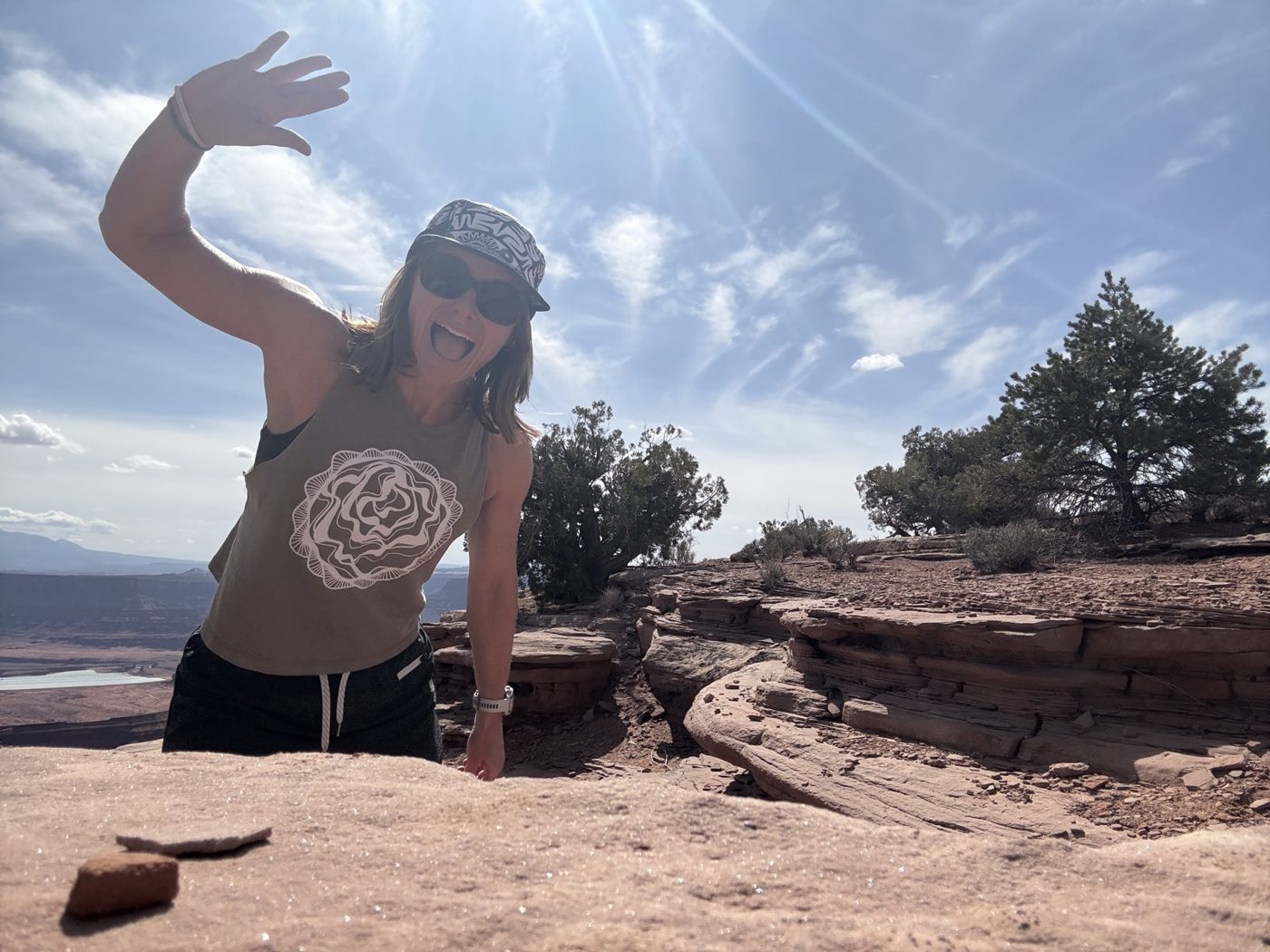 Ren waving from a sandstone ledge at Arches National Park