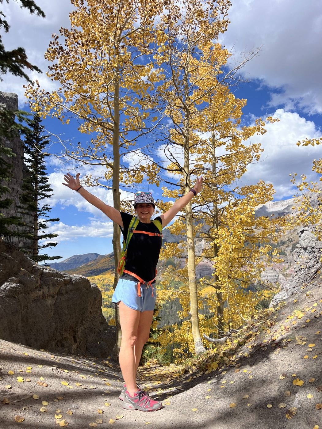 Ren with arms raised beneath golden aspens above Telluride, Colorado